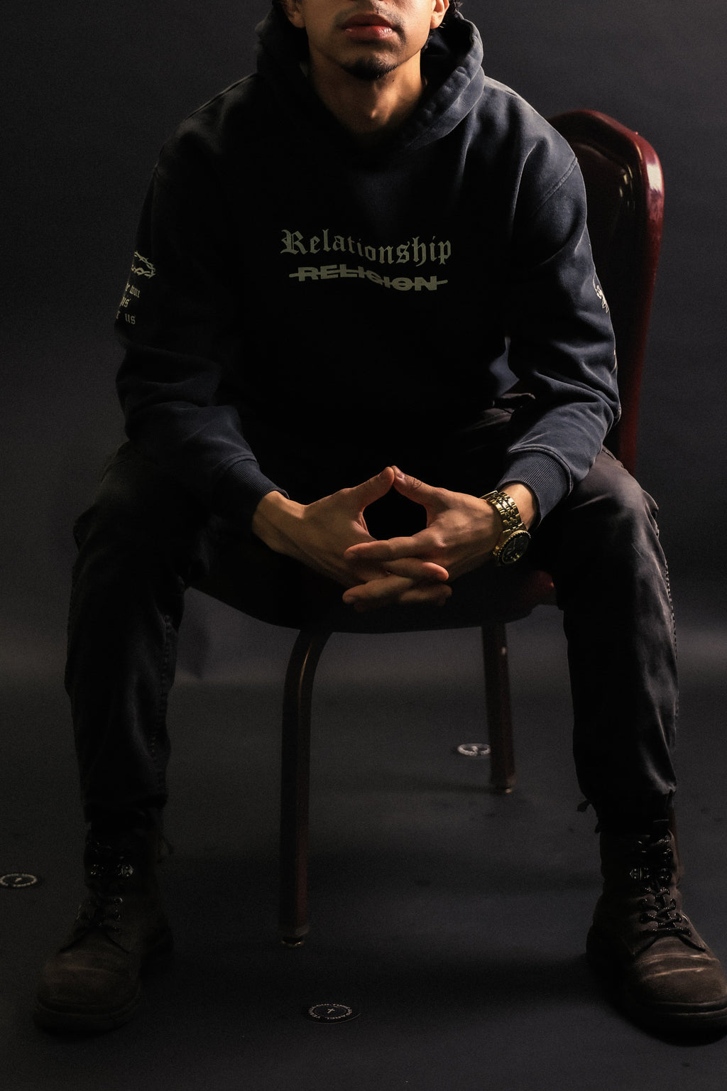 Man wearing ABOVE RELIGION oversized Christian hoodie in dark studio setting