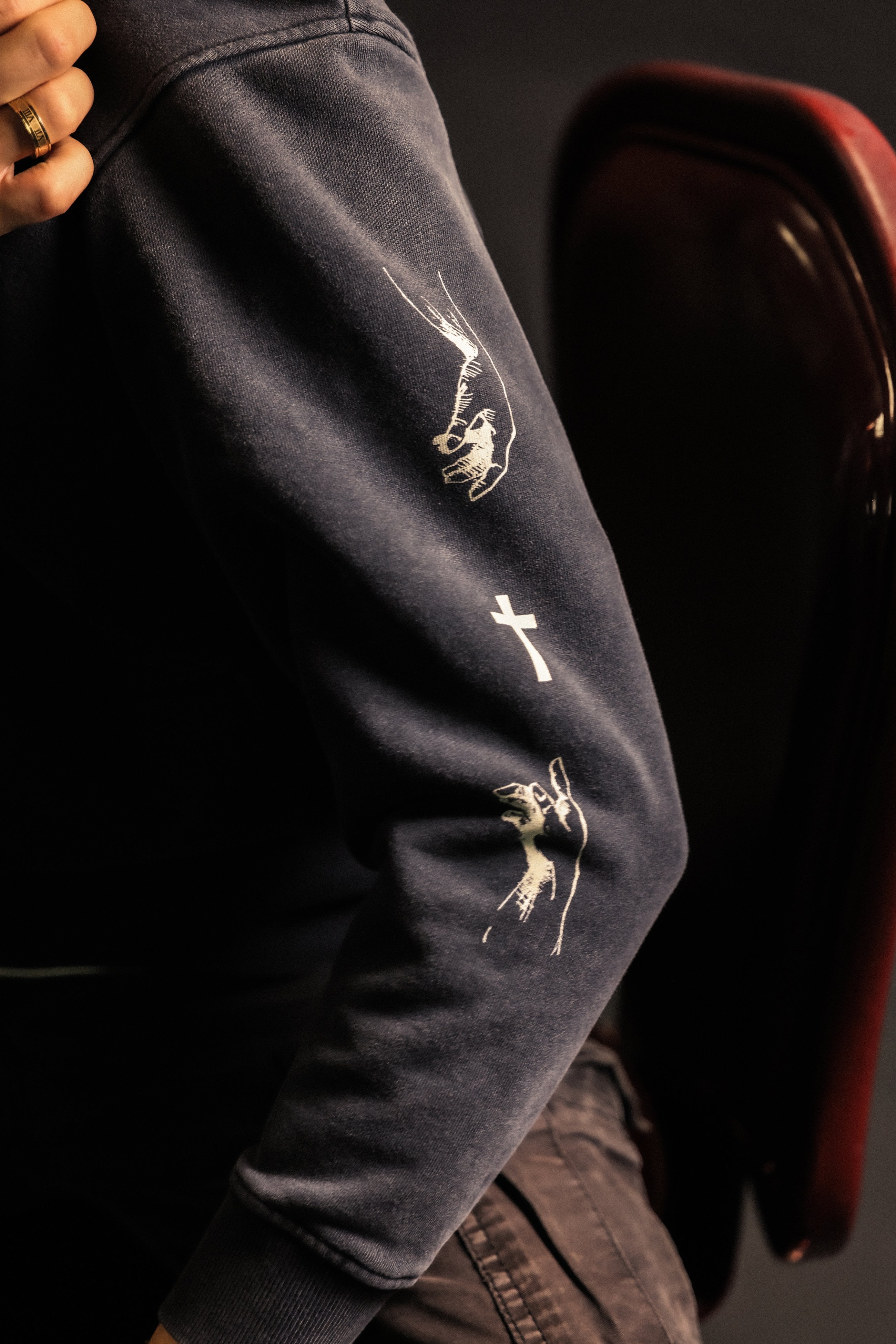 Sleeve detail on ABOVE RELIGION Christian hoodie featuring cross icon