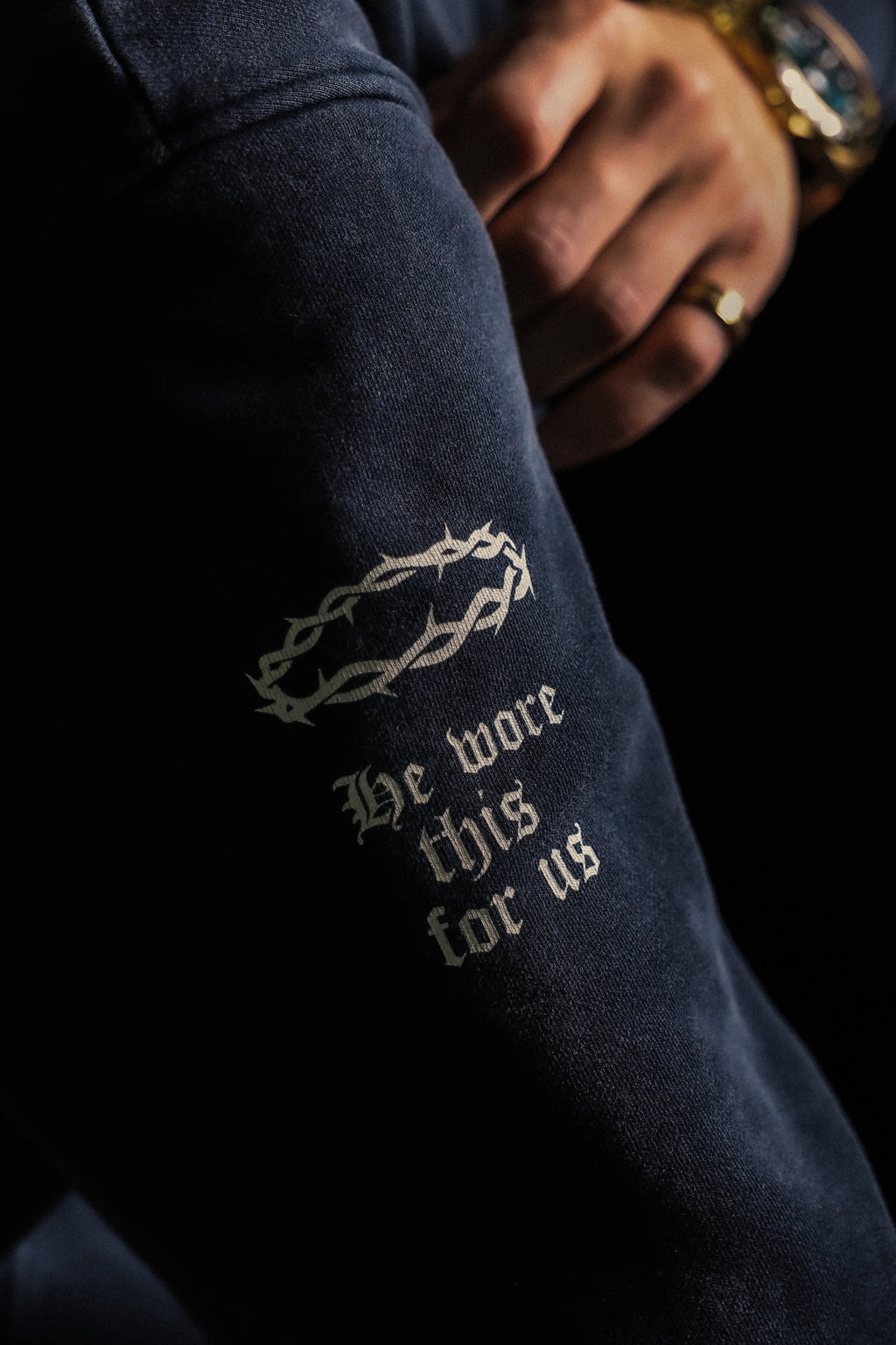 Sleeve print reading "He wore this for us" on ABOVE RELIGION hoodie