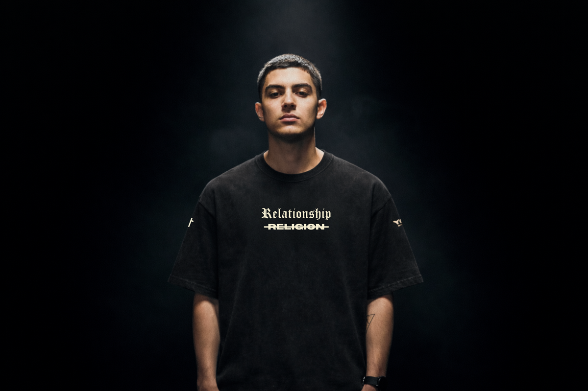 Man wearing ABOVE RELIGION Christian tee, front view, dark studio lighting