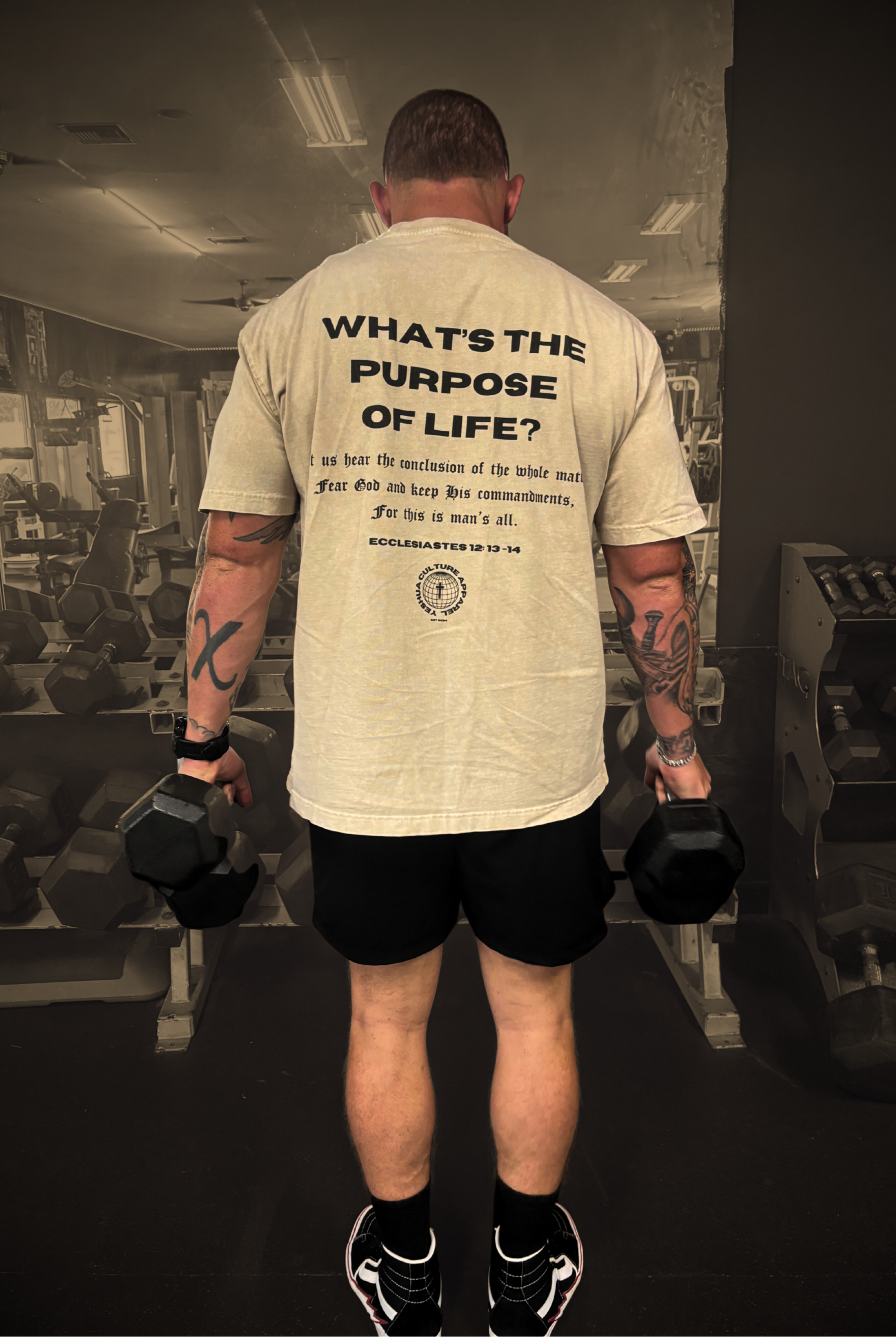 Back shot of model in gym lifting weights wearing FEAR GOD Oversized Christian Tee — bold Christian streetwear