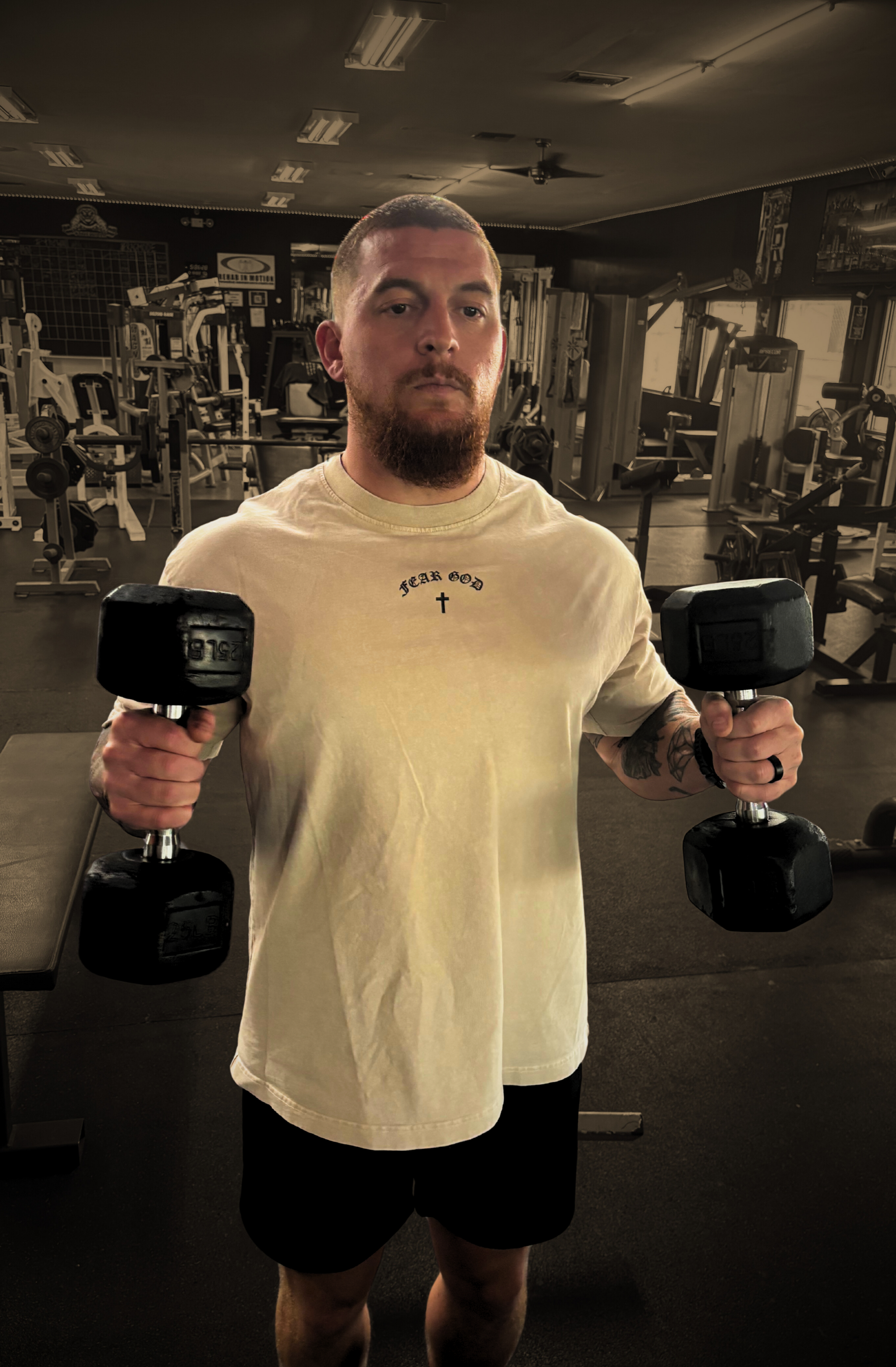 Front shot of model in gym lifting weights wearing FEAR GOD Oversized Christian Tee — bold Christian streetwear