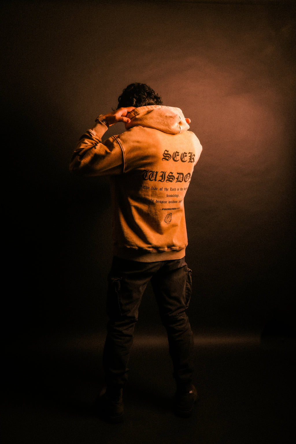 Man wearing SEEK WISDOM Christian hoodie in warm-lit lifestyle photo