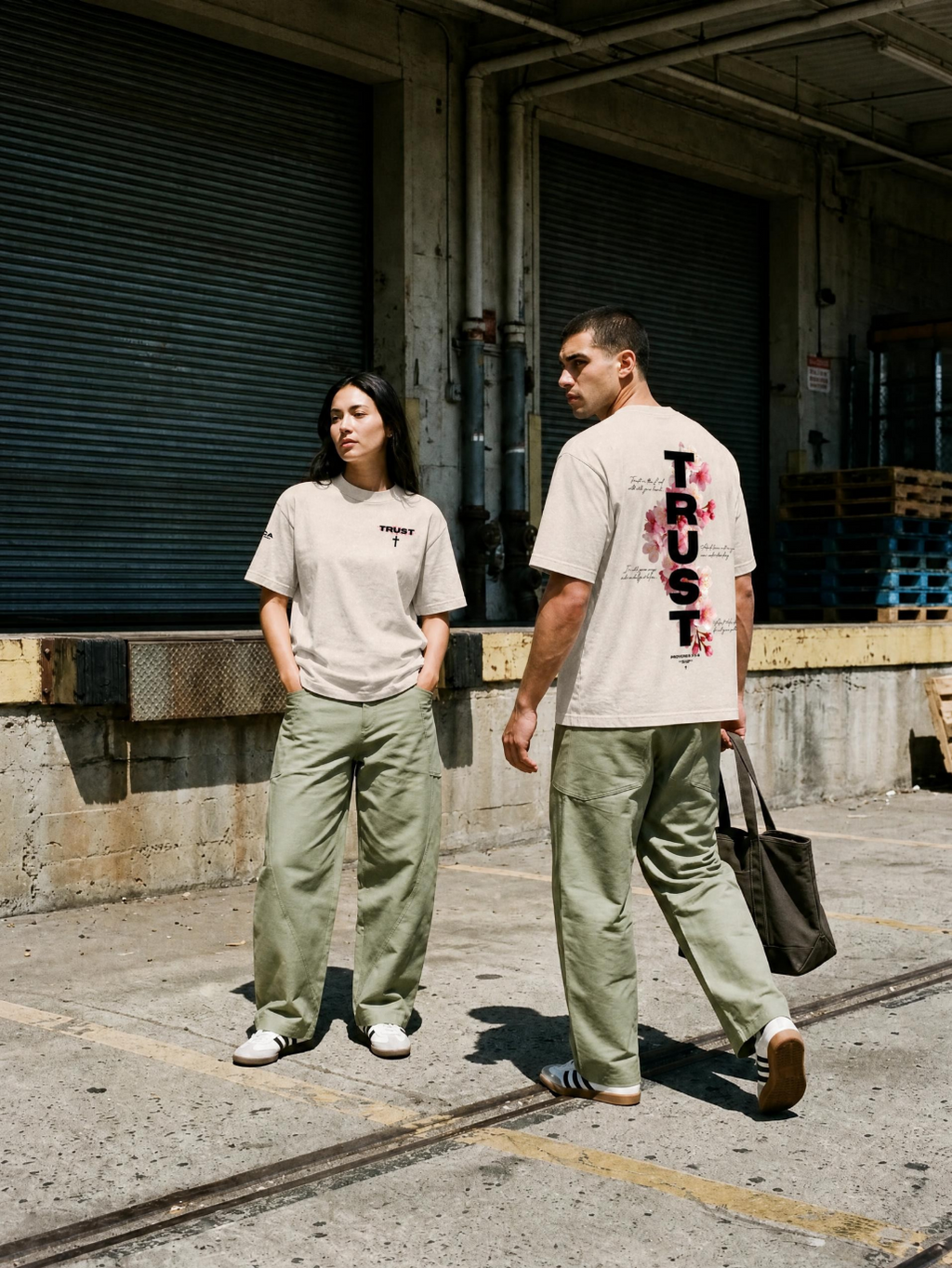 Couple walking in oversized TRUST Christian tees, faith-based streetwear