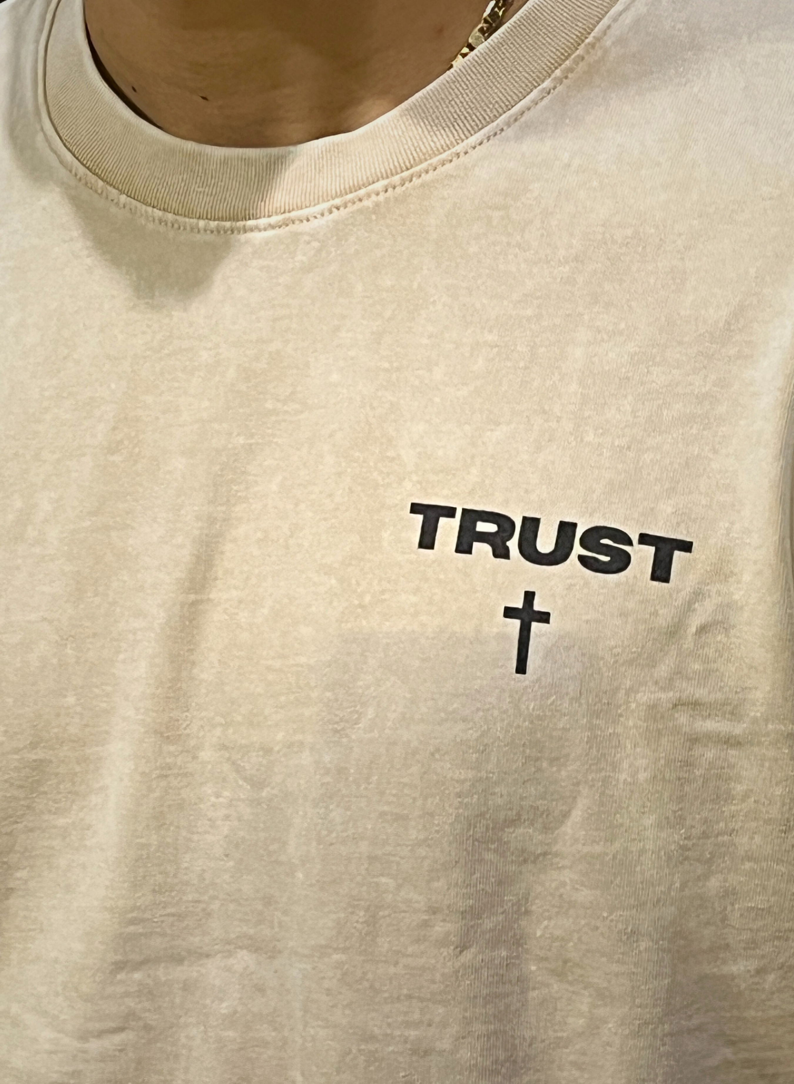 Front chest detail on TRUST Oversized Christian Tee — small TRUST + cross graphic, heavyweight cotton texture